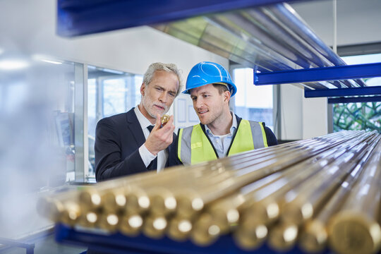 Manager discussing over metallic bolt with supervisor in factory