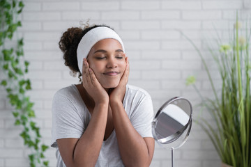 Woman with eyes closed applying cleansing foam on face at home