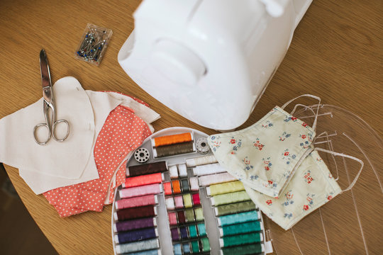 Sewing items with floral protective masks on table at home