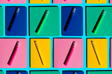 Pattern of colorful notebooks and matching felt tip pens