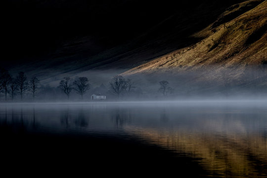 Dawn mist rises around Buttermere, the lake in the English Lake District in North West England. The adjacent village of Buttermere takes its name from the lake. Historically in Cumberland, the lake is now within the county of Cumbria. It is owned by the National Trust, forming part of its Buttermere and Ennerdale property