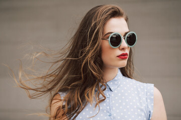 ortrait of a woman with green sunglasses on a windy day