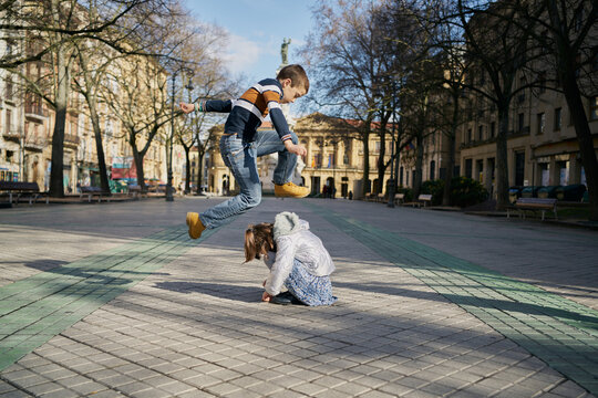 Side view of boy jumping over girl on street