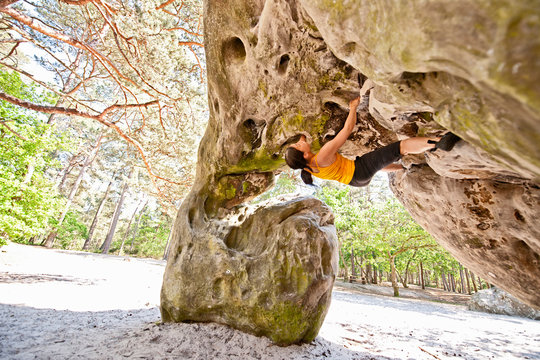 mature woman bouldering in the forest of Fontainebleau close to Paris