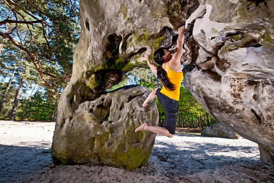 mature woman bouldering in the forest of Fontainebleau close to Paris