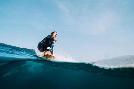 Split image of female surfer in wetsuit surfing on a longboard