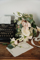 Bride's bouquet, typewriter and a set of invitations. The bride's accessories. Wedding morning. Copy space.