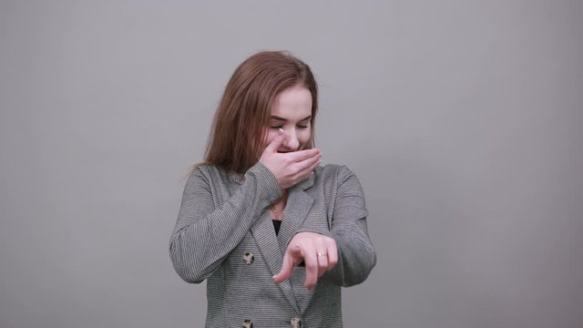 Hand pointer with forefinger pointing forward. Index finger to show direction. Means choosing, introducing too. Indicating towards. Young attractive woman, dressed gray jacket, with green eyes