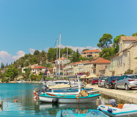 Fototapeta na wymiar Waterfront view of a tiny village of Bobovisca on the island of brac. Crystal clear teal and green water reflection the bright sky. Small boats docked in the harbour
