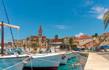 Fototapeta na wymiar Beautiful panoramic picturesque view of a small town of Milna on the island of Brac. Old boats docked in the crystal clear sea, warm summer day. Old church belltower rising above the buildings