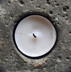 White candle in porous rock hole.
