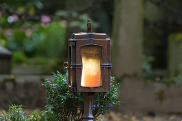 Grave lantern with burning candle in a cemetery
