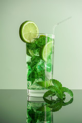 mojito cocktail in a glass high glass with lime, mint and ice on a light background