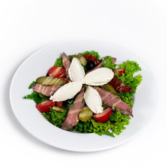 Salad with meat, cheese and vegetables on a white plate. Top view