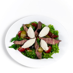 Salad with meat, cheese and vegetables on a white plate. White background