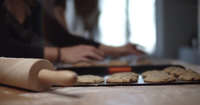 Mother in kichen takes cookies off baking tray ready to serve them to her family