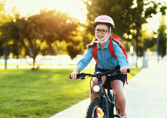 Funny girl goes to school on a bicycle.