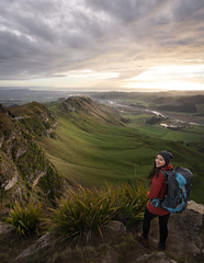 Fototapeta premium Young woman with backpack posing at the top of a mountain. Vertical photography