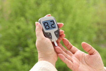 close-up female hands, woman makes a test with a glucometer in nature, medical concept, blood glucose control, diabetes