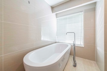 Fototapeta na wymiar Shower room with external daylight window and modern white ceramic bath