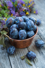 Ripe plum in a copper vintage bowl on an old wooden background.