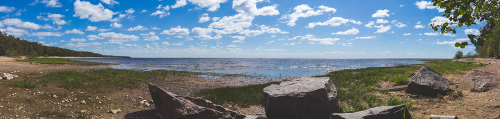 Fototapeta na wymiar Coastline panorama. seascape with horizon line. sky with clouds. stones on the shore