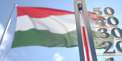 Thermometer shows high air temperature against blurred flag of Hungary. Hot weather forecast related 3D rendering