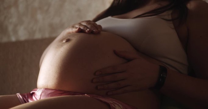 Pregnant girl stroking naked belly