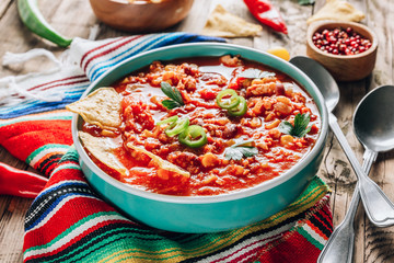 Chili Con Carne in bowl with tortilla chips on wooden background. Mexican cuisine.