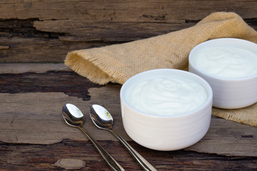 Yogurt greek white clean In bowl with spoon on a wooden background from top view.
