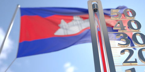Thermometer shows high air temperature against blurred flag of Cambodia. Hot weather forecast related 3D rendering