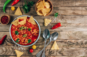 Chili Con Carne in bowl with tortilla chips on wooden background. Mexican cuisine.