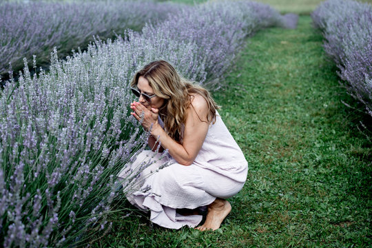 A woman smells flowers lavender in a field.