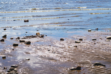 Stones on wavy wet sand. pebbles on the seashore. abstract background
