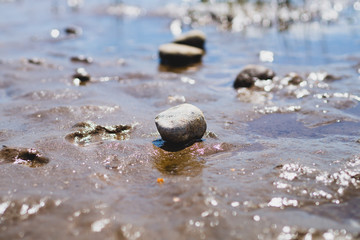 Stones on wavy wet sand. pebbles on the seashore. abstract background