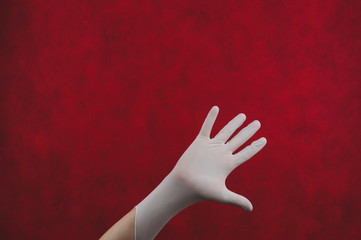 Palm of hand in medical glove on a red background. gesturing hand in white protective glove