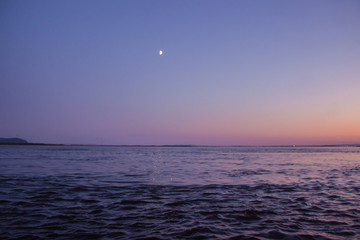 Landscape Night Photos. Moon after sunset on the side of the moon. Water surface. Night sky.