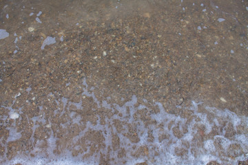 Sea wave at sea. Beach with stones and shells.