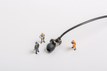 Headphones and miniature workers on white background