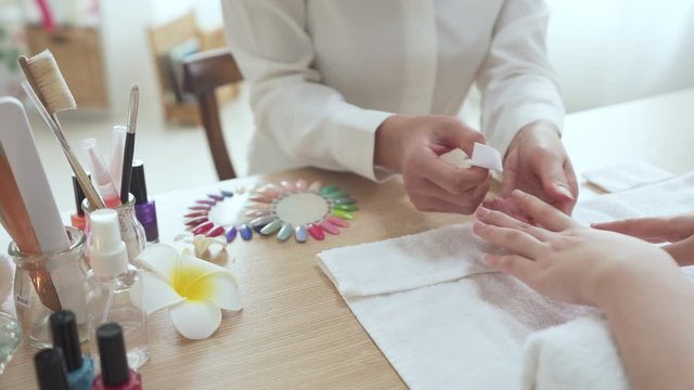 professional manicurist using a gauze to clean up the nail polish of a customer. fashion and beauty concept
