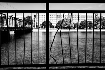silhouette of a fence over a river with city building in the background.