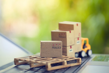 Logistic and cargo freight concept: Fork-lift a truck moves a paper box on notebook keyboard in the...