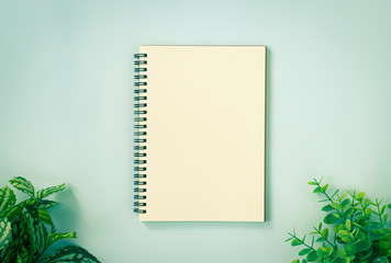 Spiral Notebook or Spring Notebook in Unlined Type and Office Plants at Bottom on Blue Pastel Minimalist Background in Vintage Tone