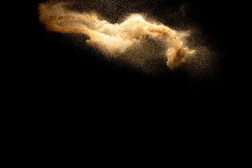 Fototapeta na wymiar Abstract motion blurred brown color sand splash against black background.