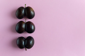 Ugly plums on pink background with copy space. Horizontal