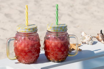 Smoothie. A red watermelon cocktail in a trendy mug stands on the edge of a chaise lounge. A healthy and refreshing drink on a hot summer day. Yummy.