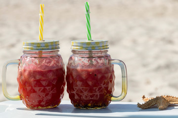 Smoothie. A red watermelon cocktail in a trendy mug stands on the edge of a chaise lounge. A healthy and refreshing drink on a hot summer day. Yummy.