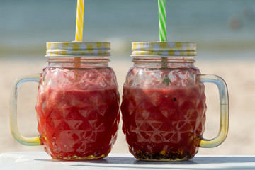 Smoothie. A red watermelon cocktail in a trendy mug stands on the edge of a chaise lounge. A healthy and refreshing drink on a hot summer day. Yummy.