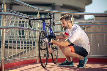 Handsome young man in sportswear inspecting bicycle