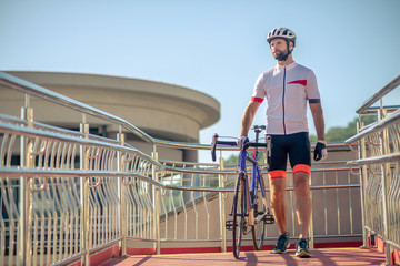 Fototapeta na wymiar Tall male cyclist walking with bike outdoors